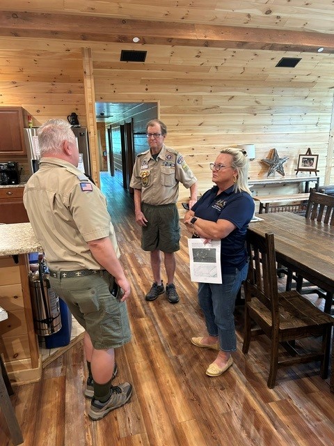 Senator Judy Ward speaking with scout masters in a cabin kitchen and dining area.